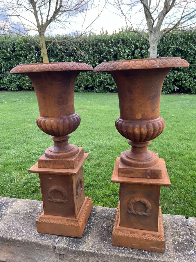 Pair of cast iron campagna urns on plinths