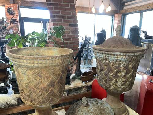 Pair of antique cast iron urns on stone plinths.